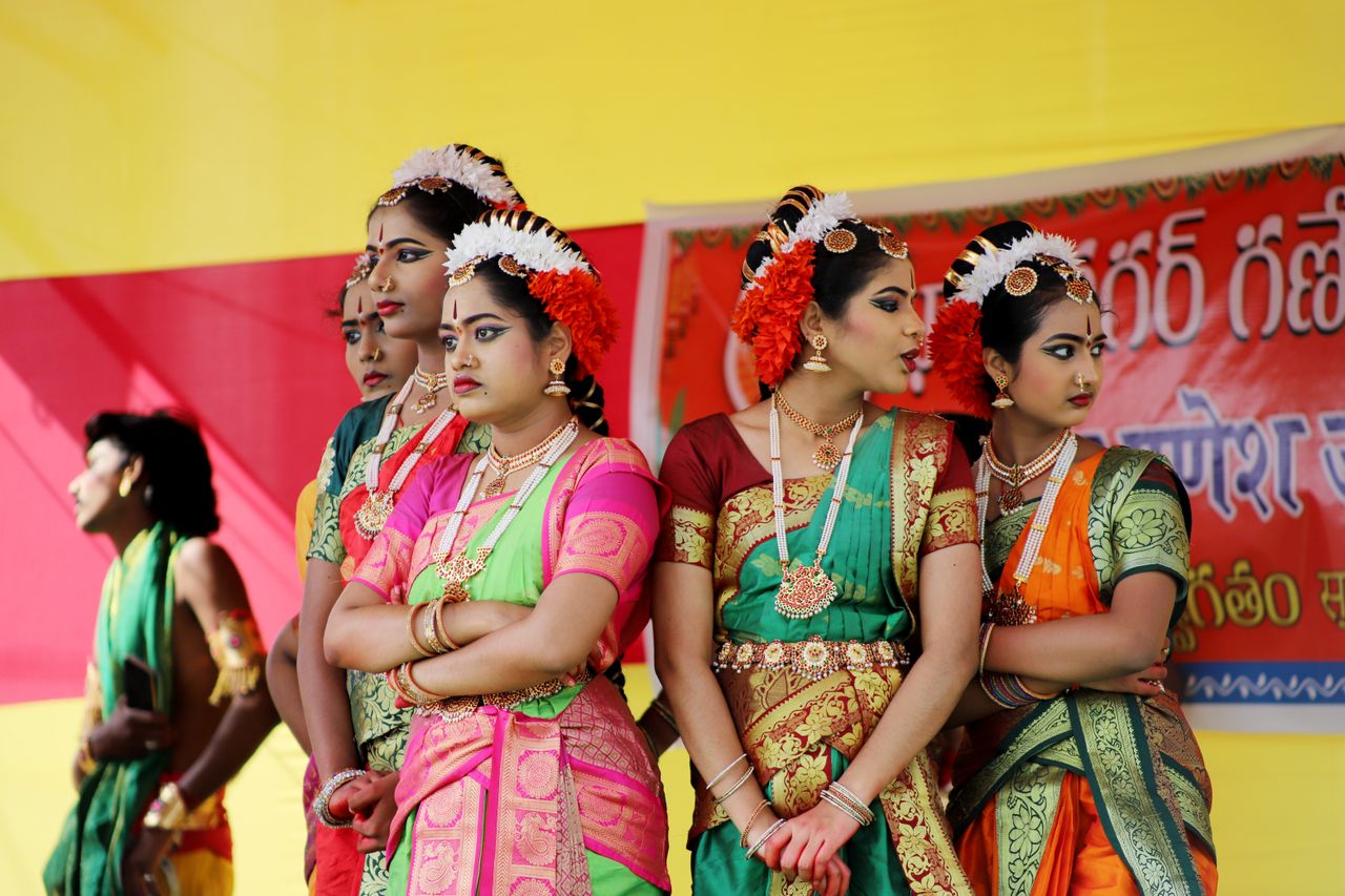 Indian dancers in traditional attire performing at a cultural festival outdoors.