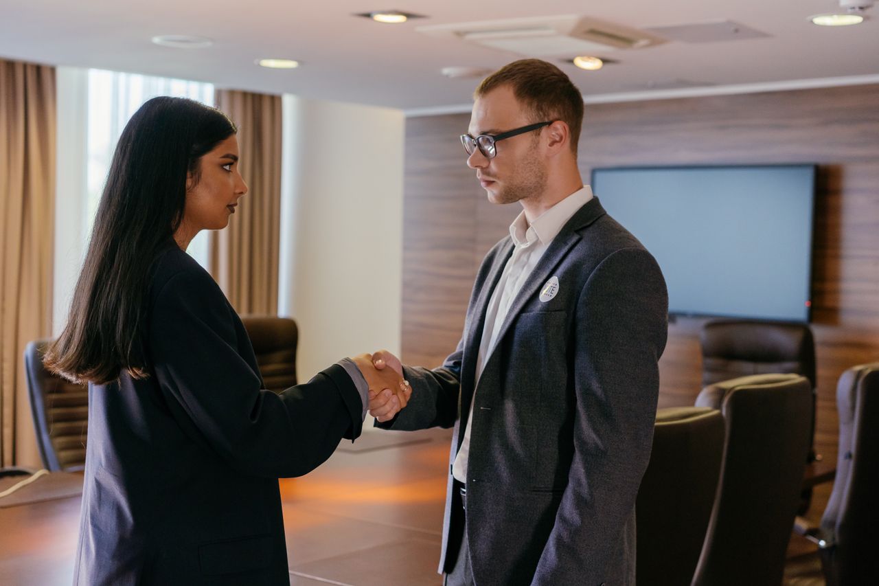 The Art of Drawing Readers In: Your attractive post title goes here Two professionals shaking hands in a modern conference room, symbolizing successful business agreement.